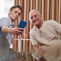 Young man taking selfie with smiling grandfather